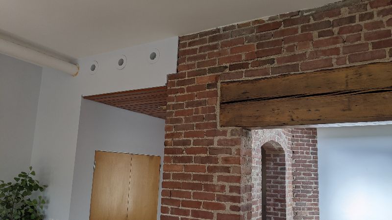 Three duct openings are above a dropped ceiling, which connects a vaulted brick mill space to a room at rear. Extensive brickwork prohibited conventional ducting in this renovation.