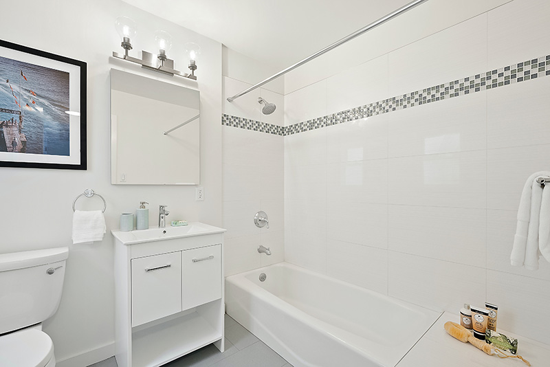 A bathroom with white walls, white shower tiles and white appliances has been newly renovated.