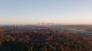 A drone image captures autumn foliage with Boston in the distance.