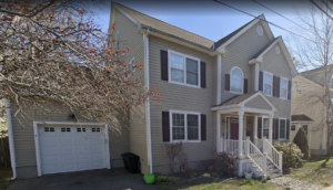 A street view image of the property at 10 Waterloo St., Hyde Park, Massachusetts. It is a two-story building with beige siding and a small lawn out front.