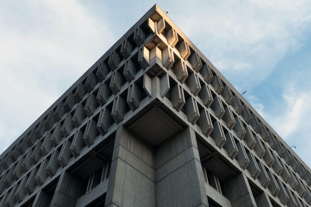 a ground-up close up view of a corner of Boston city hall, a cement building with multiple Brutalist design angles.