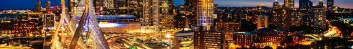 an aerial view of Boston at night, with buildings and bridges lit up against a dark blue sky.