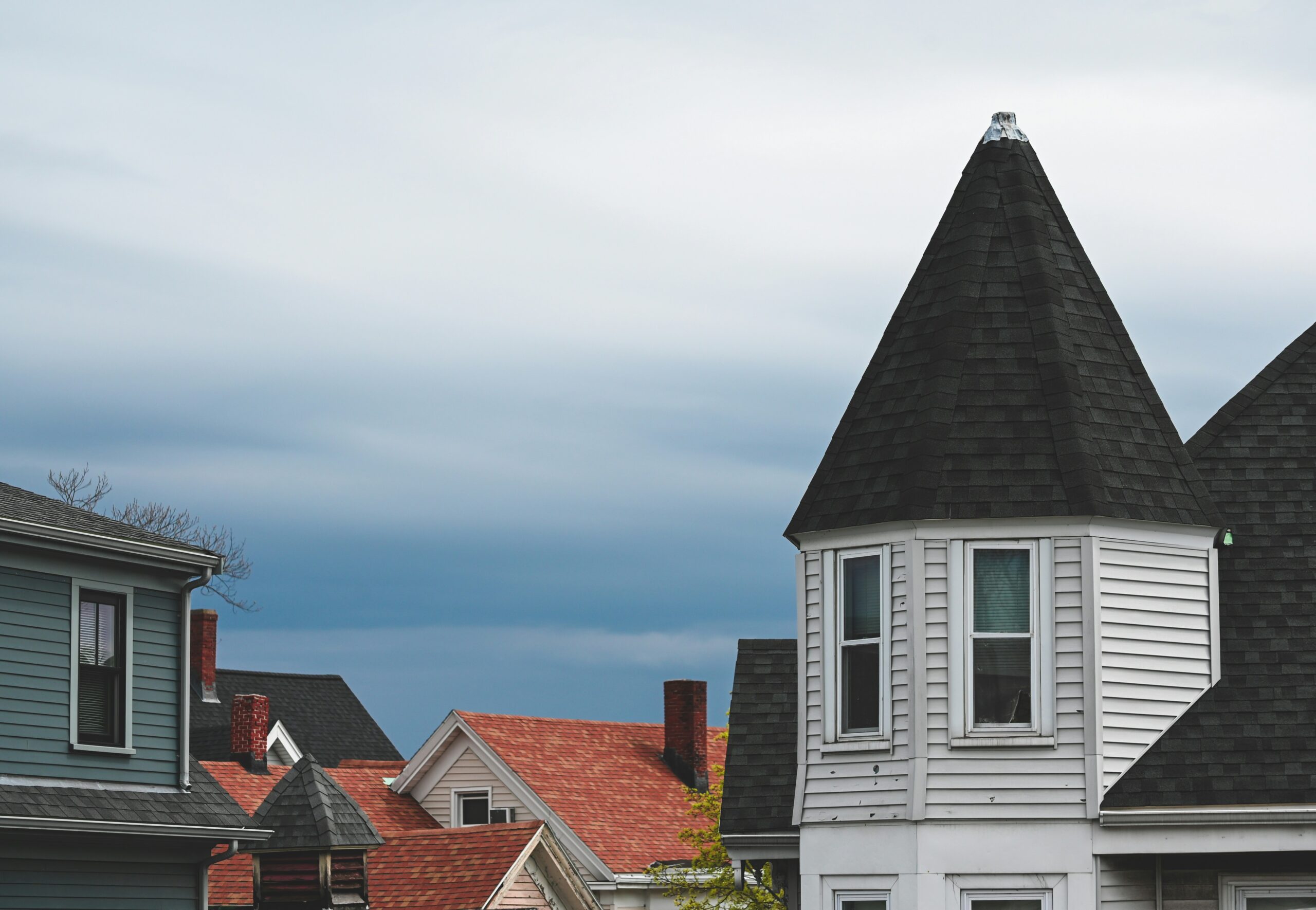A rooftop view of several homes and buildings in Allston, Mass., with steep roofs.