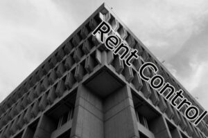 Boston City Hall looms large in a black and white photo. The words Rent Control run along its upper roof line.