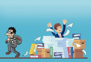 a cartoon of a businessman sitting behind a desk piled high with files and papers. His hands are in the air, and papers are flying around. Meanwhile, a robber with a bag labeled “data” sneaks away.