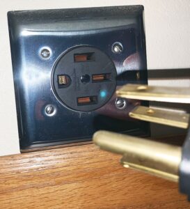 A NEMA 14-50 plug in an old building. There are three slots and one circular ground pin.