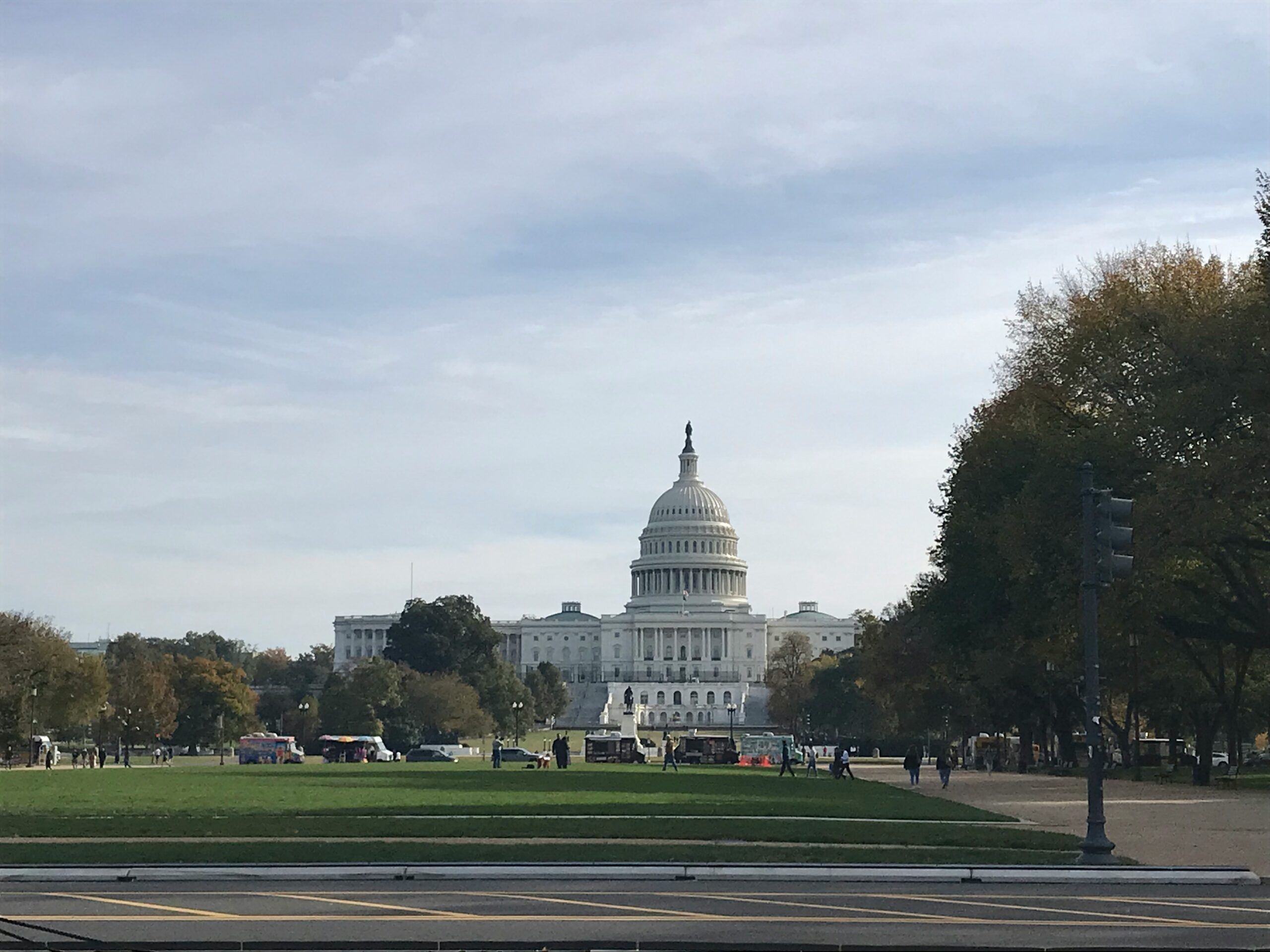A photograph of the U.S capitol building from a distance, with lawn in the foreground.