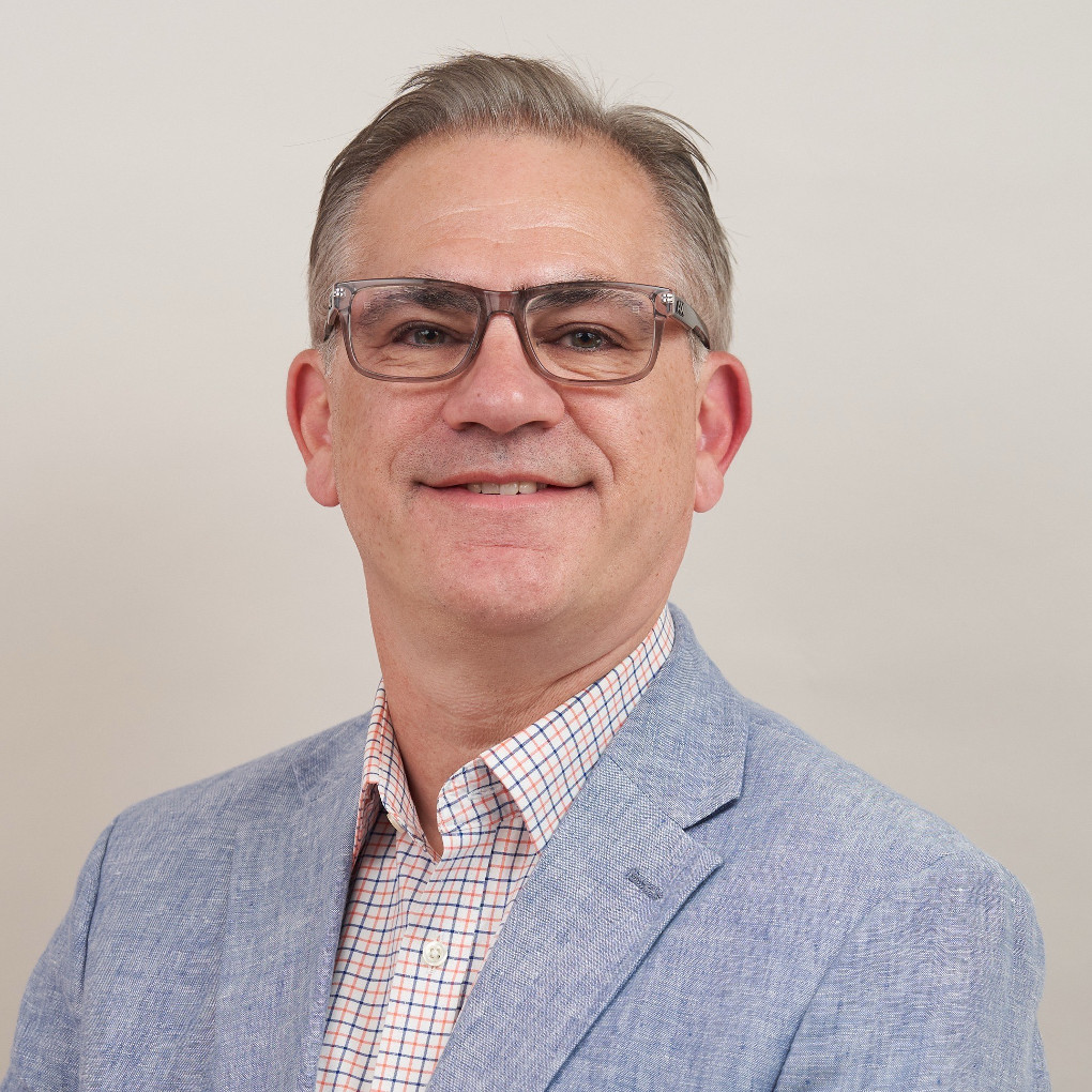 Don wears a modest suit jacket, button-down shirt and glasses. He smiles with his chin up, projecting confidence in the future.