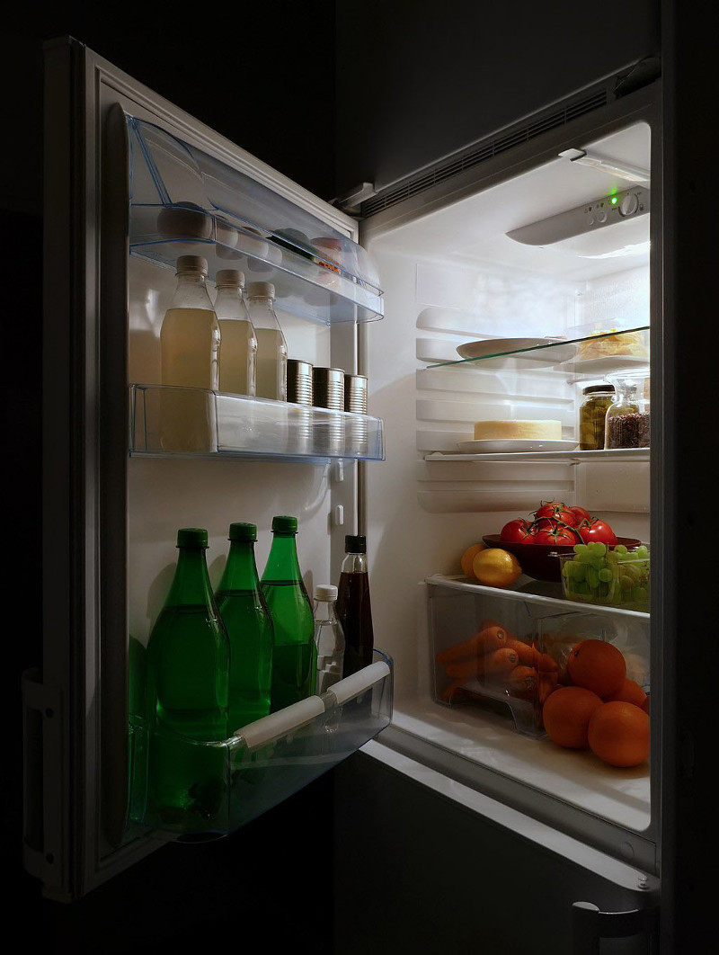 A photo of a refrigerator with doors open, showing bottles of soda, water and fruit and vegetables.