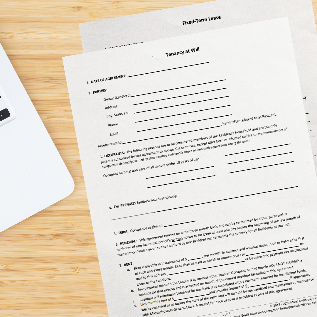 A wooden desktop shows the corner of a laptop computer, and the first page of our tenancy at will form stacked on top of the first page of our fixed-term lease agreement.