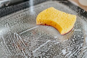 A close-up of a sponge on a soapy black countertop.