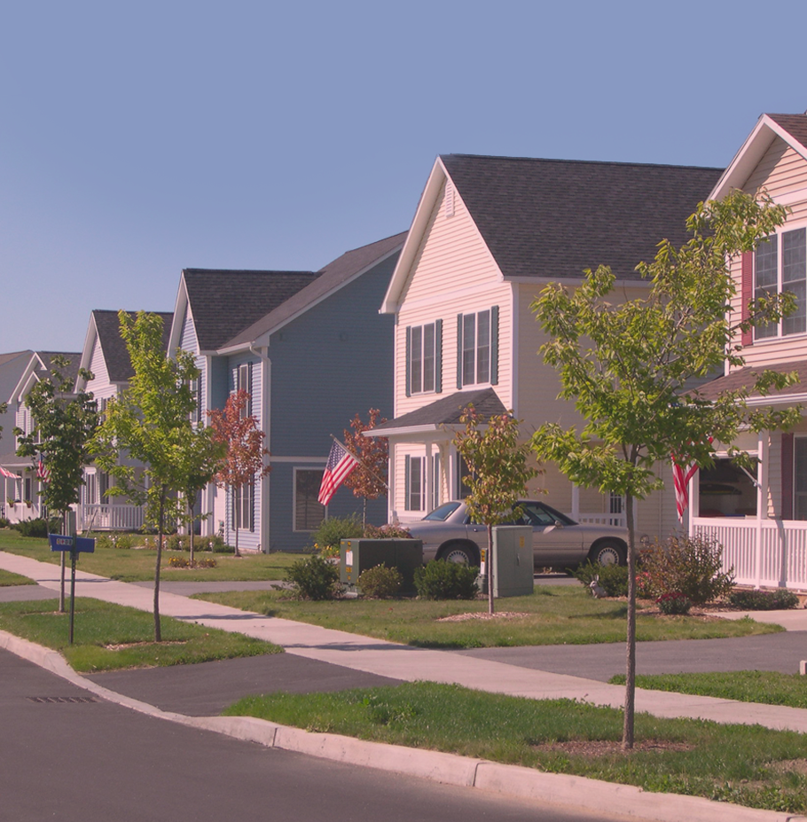 photo of a modern street lined with large single-family homes of similar two-story design, on a bright, clear day.
