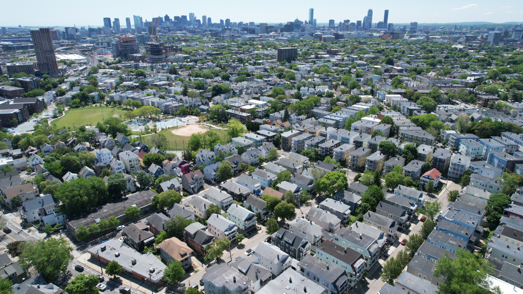 A drone photograph showing thousands of three-deckers facing a Cambridge and Boston skyline thick with towers.