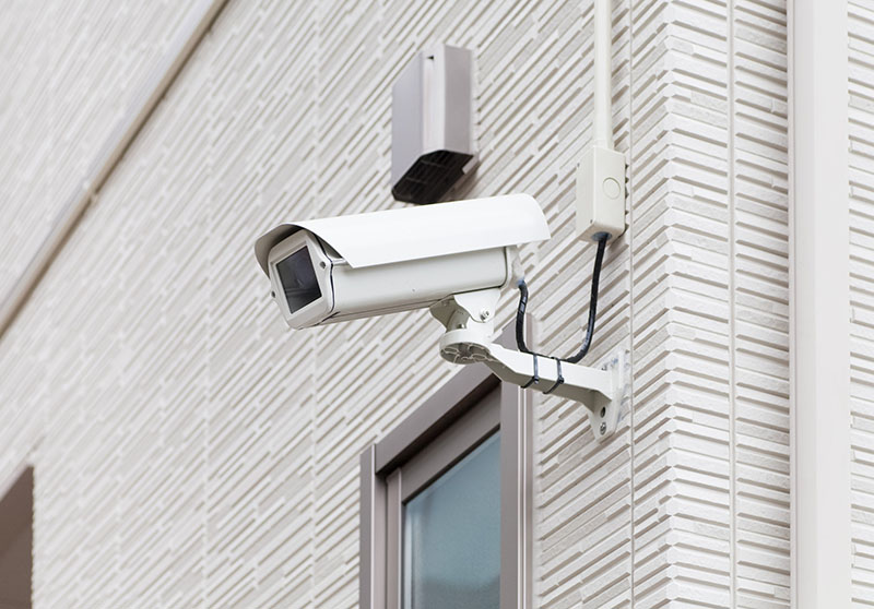 closeup photo of a security camera mounted on the exterior of a building.
