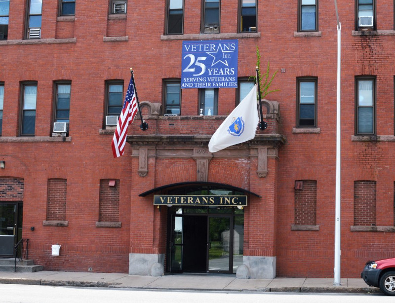 Veterans, Inc.'s brick building in Worcester flies the United States flag and the Massachusetts flag. A sign above the door says 25 years serving veterans and their families.