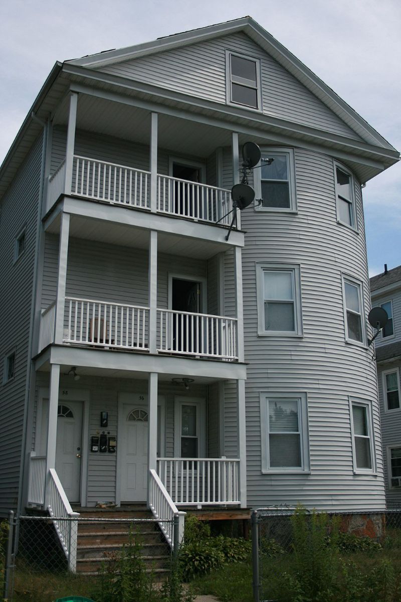 exterior photo of a gray-painted triple-decker house in Worcester.