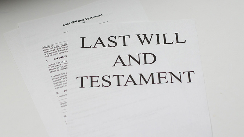 A close-up image of several pieces of white paper. The top page reads “Last Will and Testament.” The page behind it contains a last will and testament form with blank spaces to be filled out.