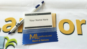 A MassLandlords branded bic pen and in-person event nametag sit on a MassLandlords tablecloth.