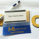A MassLandlords branded bic pen and in-person event nametag sit on a MassLandlords tablecloth.