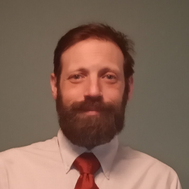 Aaron Ginsberg wears a full beard, shirt and tie.