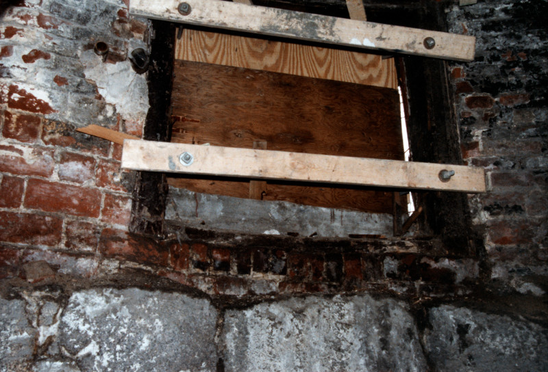 picture of basement interior showing boarded up window and loose masonry