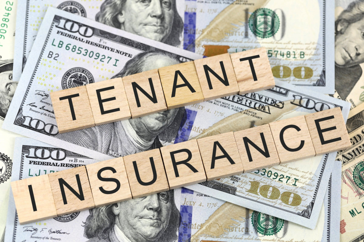 A pile of American hundred dollar bills laid over with Scrabble squares spelling out “Tenant Insurance.”