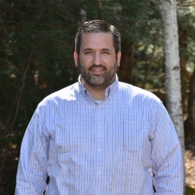 picture of Dan A. Smith of Daikin wearing a collared shirt standing in front of a forest.