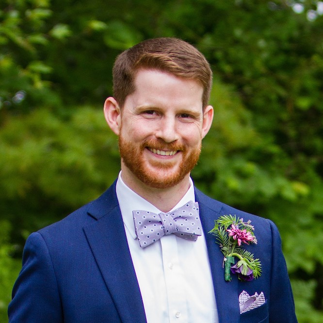 Brooks wears a short full beard and a suit and bow tie at a special occasion.